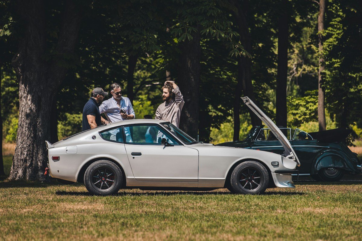 People chatting next to a Datsun 240Z