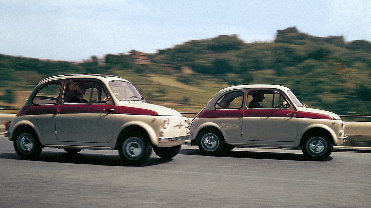 Two 1959 Fiat Nuova 500 Sport cars driving down the road
