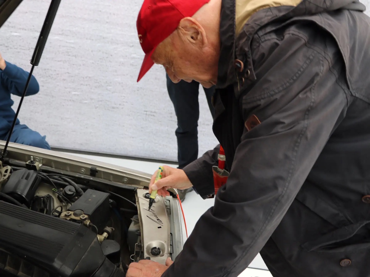 Niki Lauda signing the engine bay of a 1985 Mercedes-Benz 190 E 2.3-16 once owned by Ayrton Senna