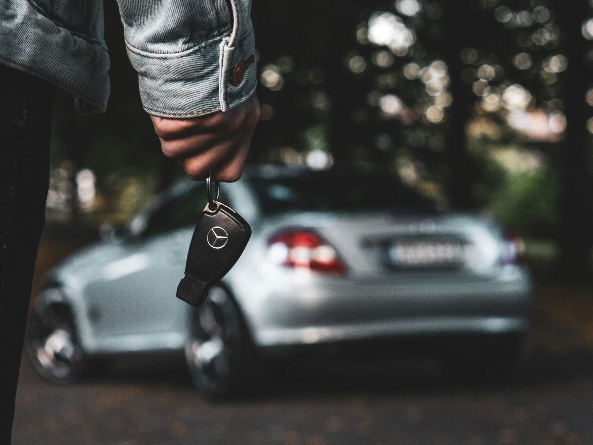 a person holding a car key next to a silver car