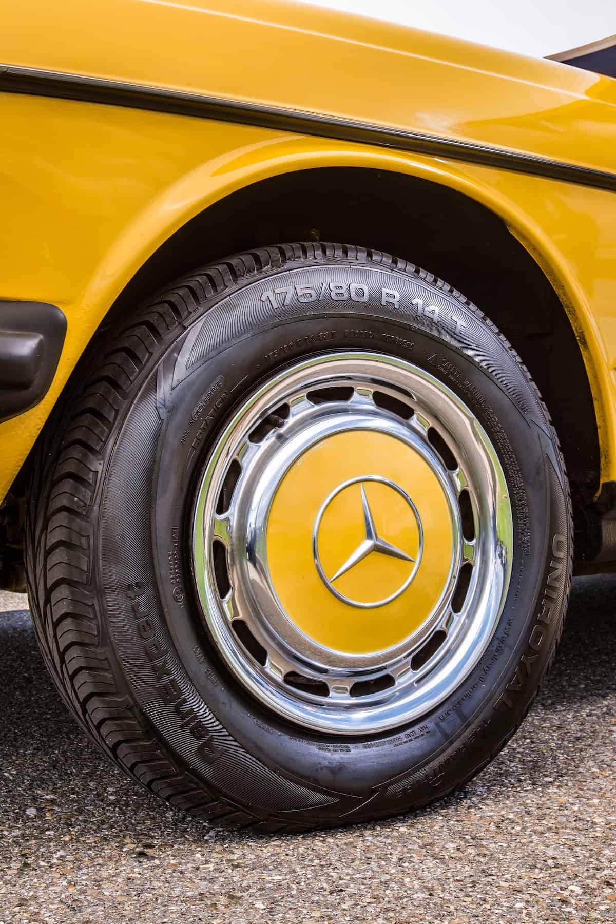 Mercedes-Benz 230 der Baureihe 123. Detailaufnahme des linken Vorderrads mit klassischer Radkappe. (Fotosignatur der Mercedes-Benz Classic Archive: D290454) Mercedes-Benz 230 of the 123 model series. Detailed view of left front wheel with classic hub cap. (Photo index number in the Mercedes-Benz Classic Archive: D290454)