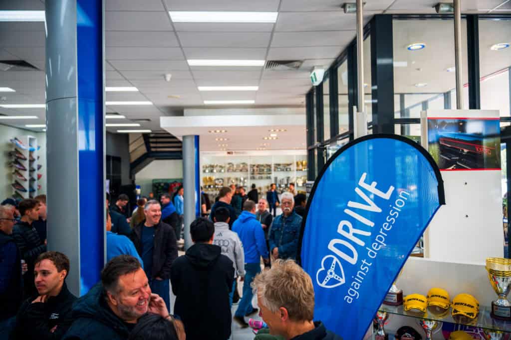 Drive Against Depression banner and crowd at Tickford Racing headquarters