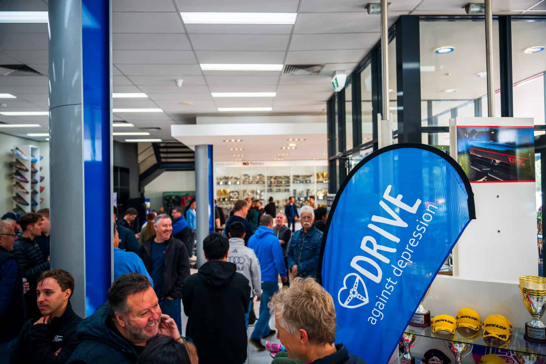 Drive Against Depression banner and crowd at Tickford Racing headquarters