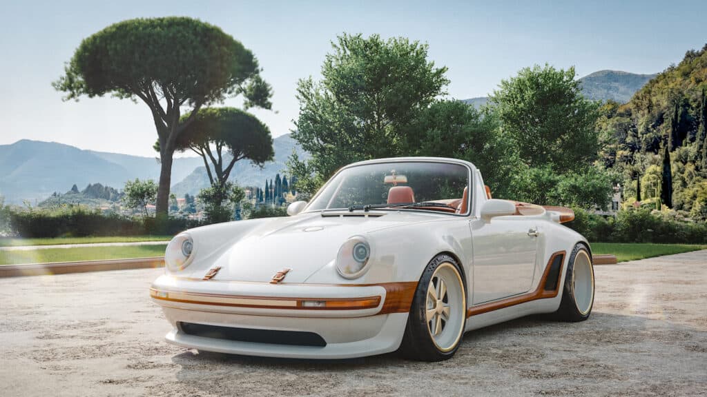 Front ¾ view with roof lowered, showing carbon fibre bodywork in Calcaire Lutétien White with wood accents and leather hood fastening straps