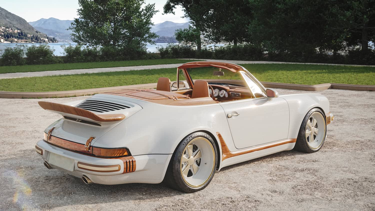 Elevated rear ¾ view with roof lowered, showing rear luggage cover with wood inlay and leather fastening straps for rear engine cover.