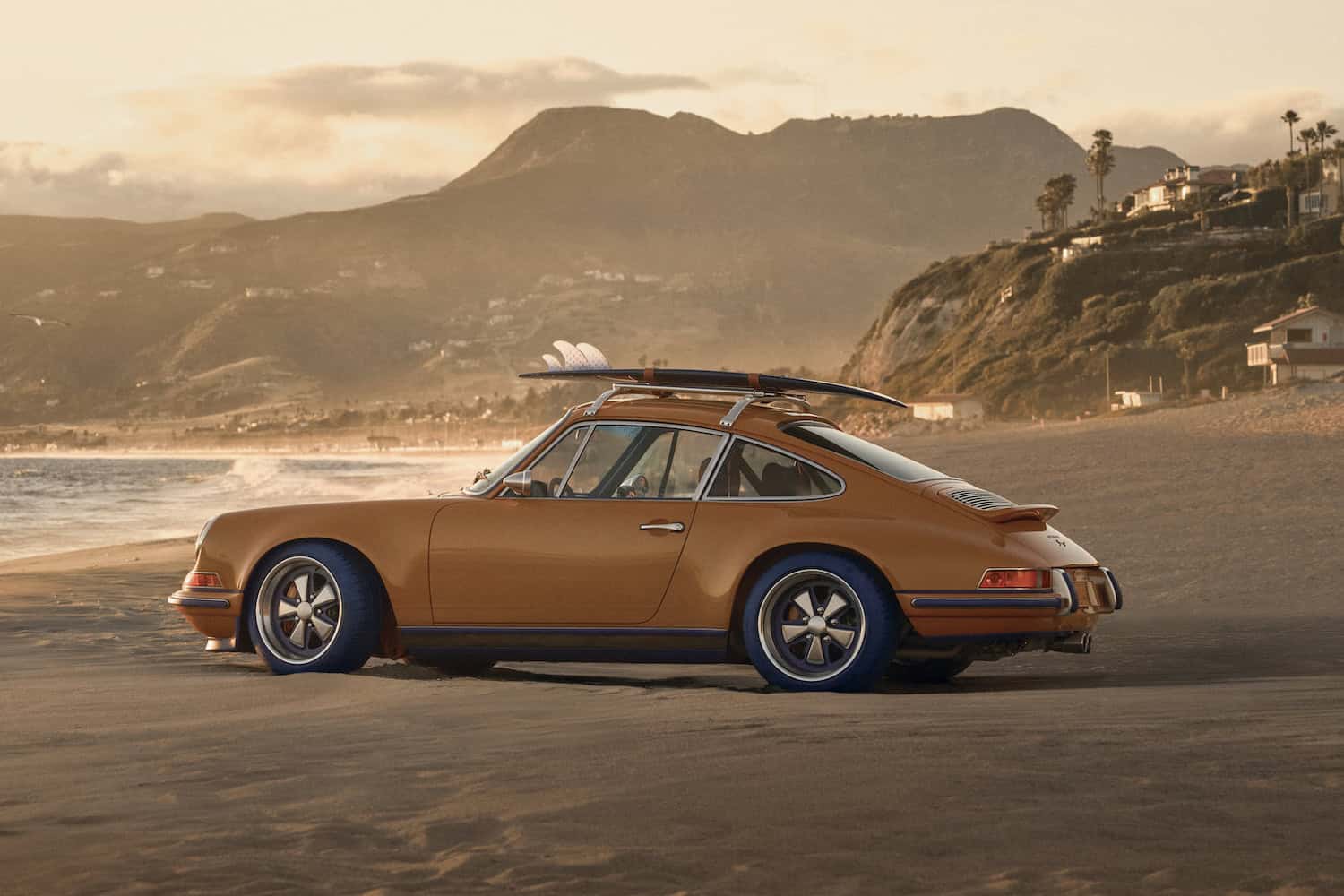 Side exterior profile showing carbon fibre bodywork presented in Saffron, with roof rack and surfboard fitted. Powered by 4.0L naturally aspirated flat-six.